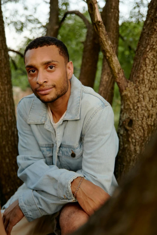 a man sitting in a tree looking at the camera, by Stokely Webster, light skin tone, young adult male, raffael, slightly smiling