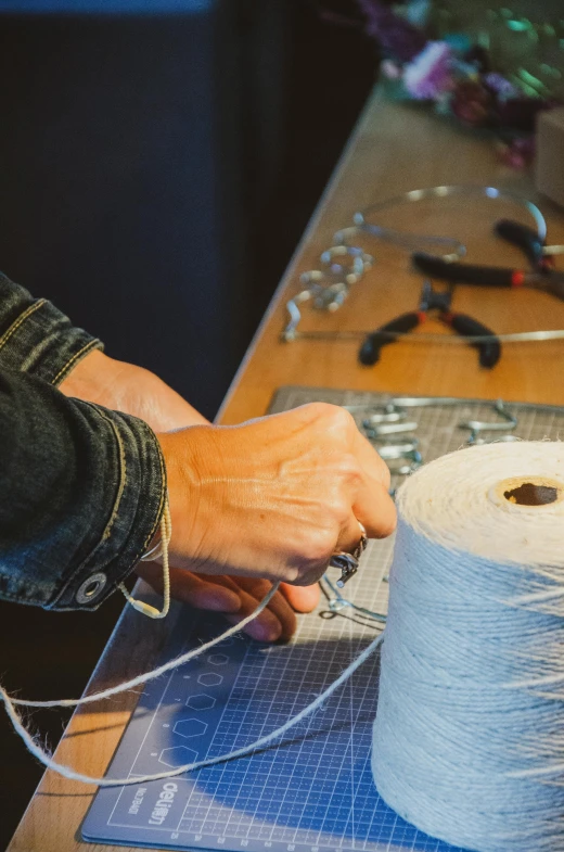 a person working on a spool of yarn, an album cover, by Glennray Tutor, unsplash, arbeitsrat für kunst, featuring rhodium wires, in a workshop, ignant, sustainable materials