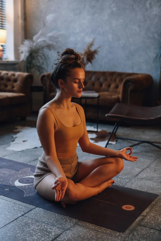 a woman sitting on a yoga mat in a living room, by Adam Marczyński, pexels contest winner, renaissance, meditating pose, promo image, slate, brown