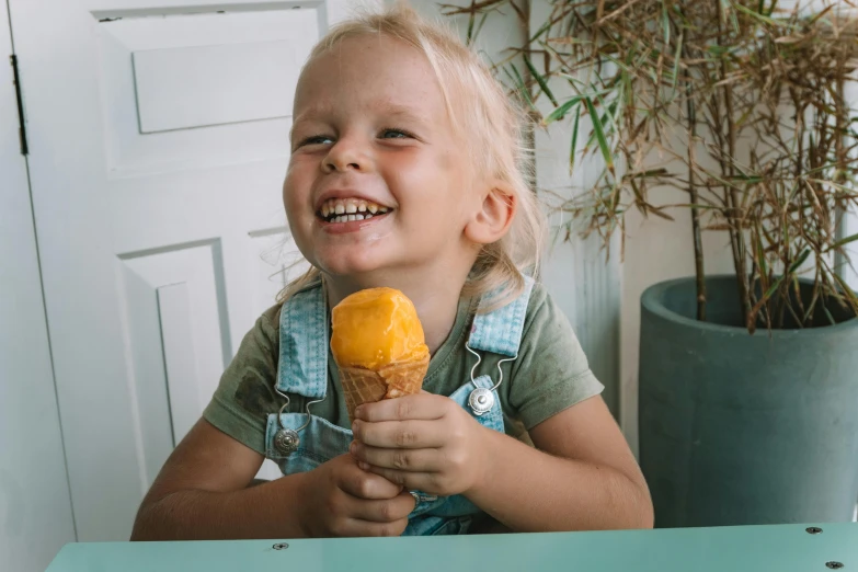 a little girl sitting at a table eating an ice cream cone, pexels contest winner, he is smiling, yellow, 15081959 21121991 01012000 4k, thumbnail