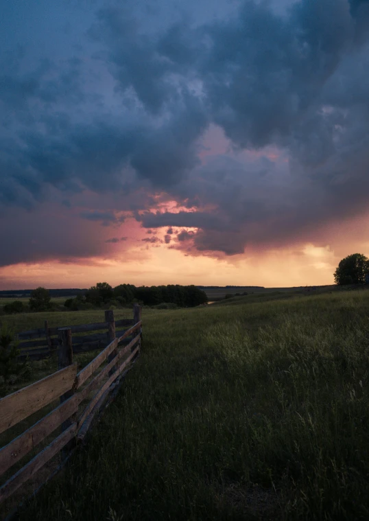 a wooden fence sitting in the middle of a field, by Sebastian Spreng, unsplash contest winner, dramatic storm sunset, panorama, humid evening, 4k)