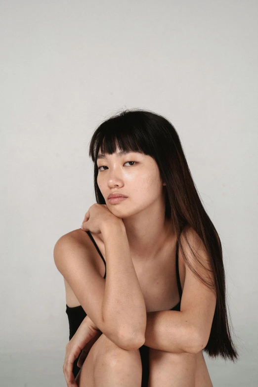 a woman sitting on the ground posing for a picture, an album cover, inspired by Kim Tschang Yeul, unsplash, realism, set against a white background, headshot profile picture, soft chin, half asian