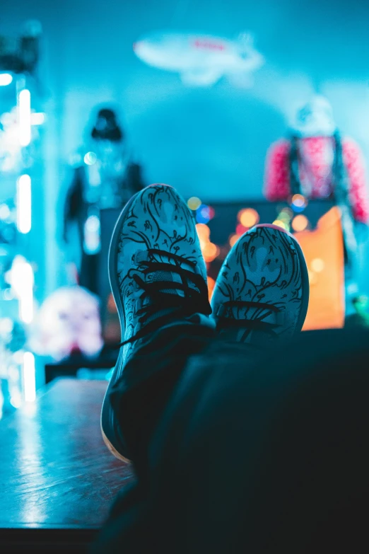 a person's feet on a table in front of a television, inspired by Elsa Bleda, trending on pexels, maximalism, blue lights, sneaker photo, sitting on a store shelf, avatar image