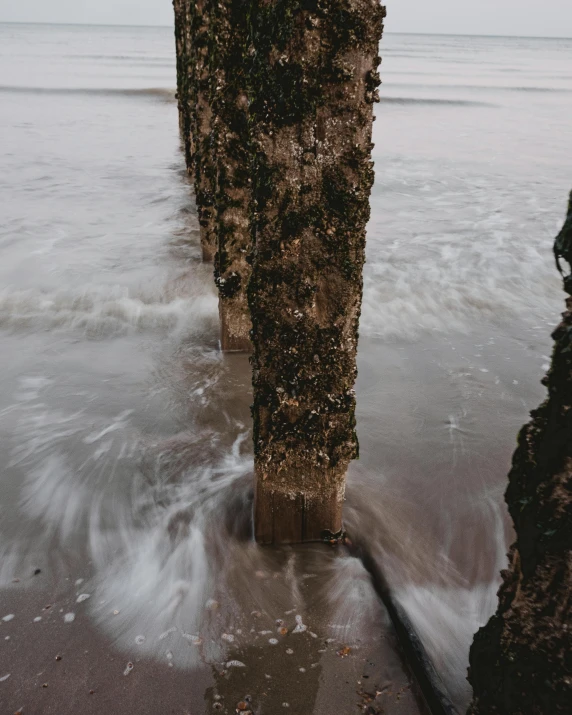 a man riding a surfboard on top of a sandy beach, a picture, by IAN SPRIGGS, unsplash, pillars of marble, with seaweed, thumbnail, rivulets