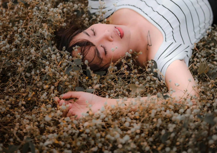 a woman laying in the grass with her eyes closed, inspired by Elsa Bleda, pexels contest winner, with soft bushes, avatar image, gypsophila, gardening