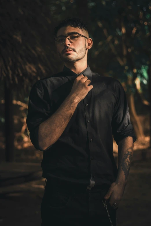 a man in a black shirt and tie, an album cover, by Byron Galvez, pexels contest winner, in jungle, casual black clothing, tight wrinkled cloath, tattooed