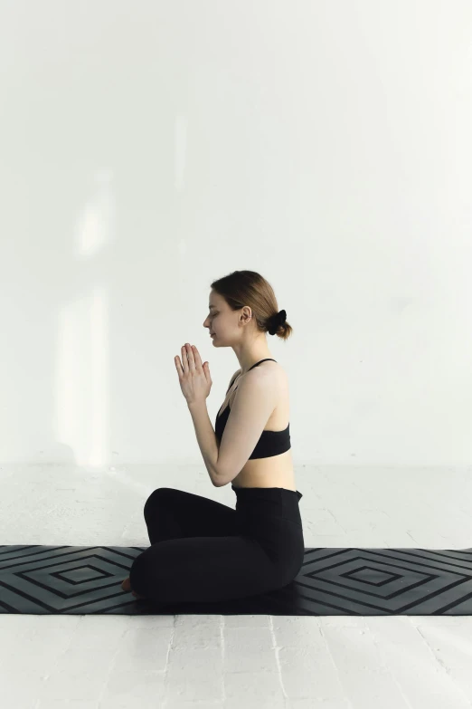 a woman sitting on a mat doing yoga, a statue, trending on unsplash, praying posture, low quality photo, full body image, anna nikonova aka newmilky