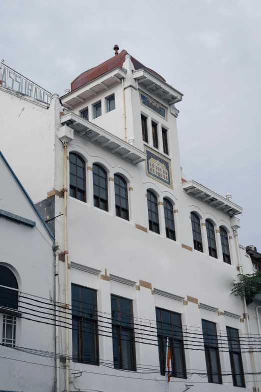 a large white building with a clock on top of it, inspired by Pedro Álvarez Castelló, quito school, manila, shutters, side elevation, view from slightly above