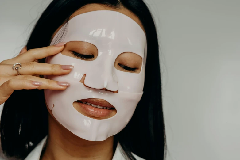 a woman putting a mask on her face, trending on pexels, mingei, latex flesh and facial muscles, glossy white, korean, square face