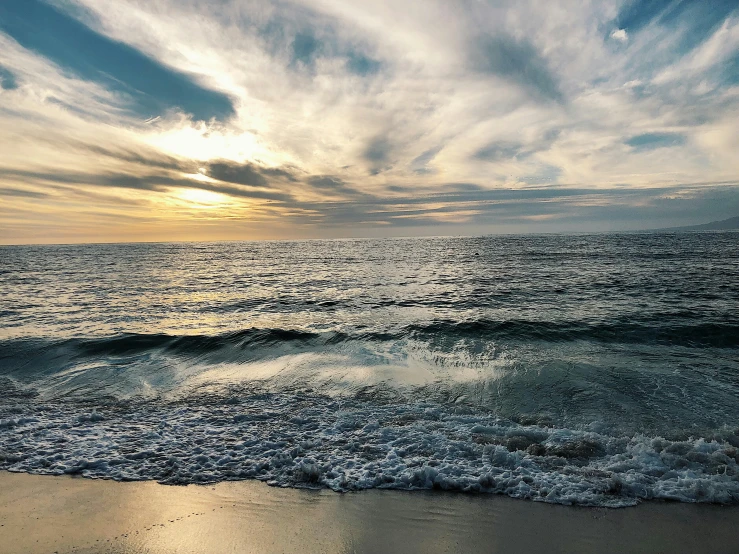 a large body of water sitting on top of a sandy beach, an album cover, unsplash, evening sun, turbulent waves, turquoise horizon, 2000s photo