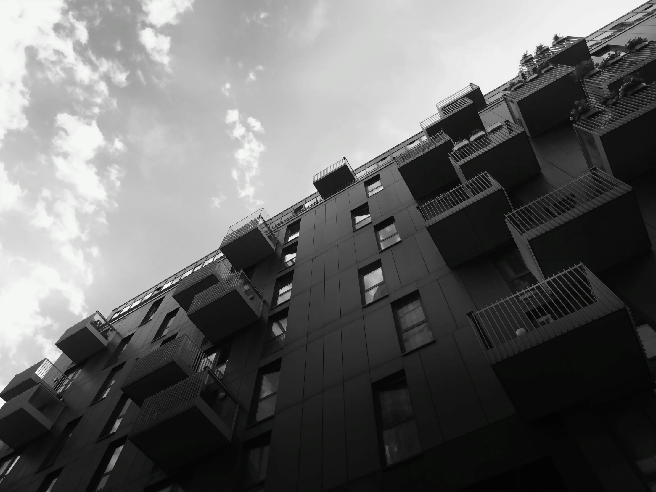 a black and white photo of a tall building, a black and white photo, unsplash, mass housing, modular, balcony, dramatic sky