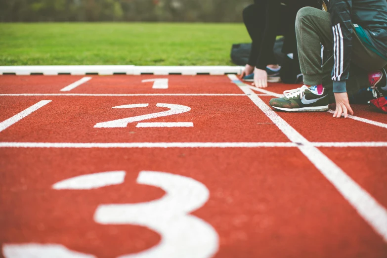 a group of people sitting on top of a red track, on the field, on a canva, profile image, sport