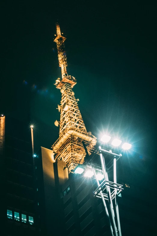 the eiffel tower is lit up at night, an album cover, unsplash contest winner, set in tokyo rooftop, crane shot, manila, close up shot from the side