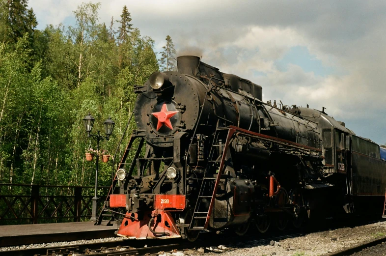 a train traveling down train tracks next to a forest, inspired by Vladimir Borovikovsky, pexels contest winner, socialist realism, black steel with red trim, big engine, kremlin, 🚿🗝📝