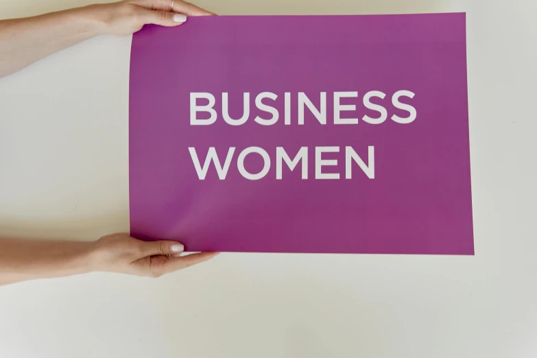 a person holding a sign that says business women, a poster, by Rachel Reckitt, trending on unsplash, on a gray background, high angle close up shot, 3 2 x 3 2, female forms