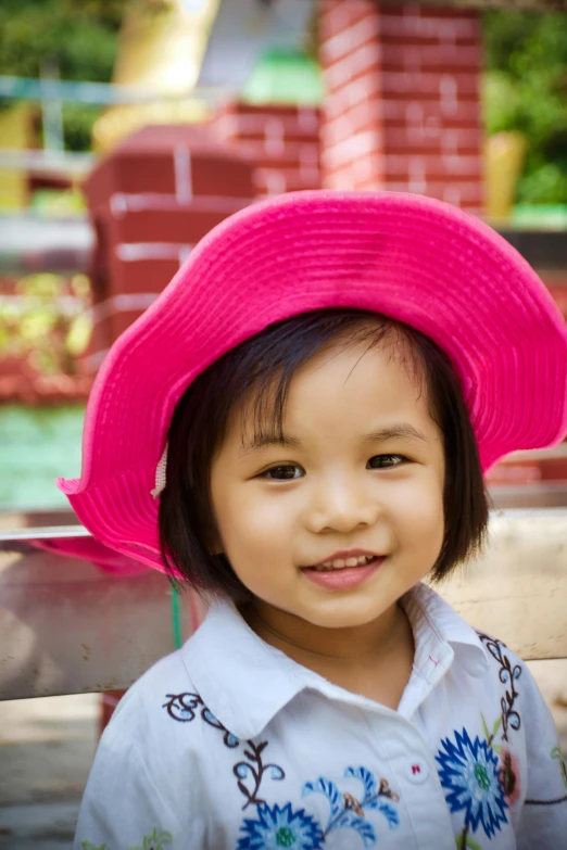 a little girl sitting on a bench wearing a pink hat, pexels contest winner, south east asian with round face, hot pink, square, taken in the late 2010s