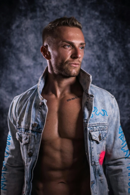 a shirtless man standing in front of a dark background, an album cover, inspired by Alexander Litovchenko, jean jacket, blue-eyed man, professional modeling, prideful look