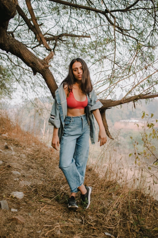 a woman standing on top of a hill next to a tree, baggy jeans, wearing crop top, profile image, canvas