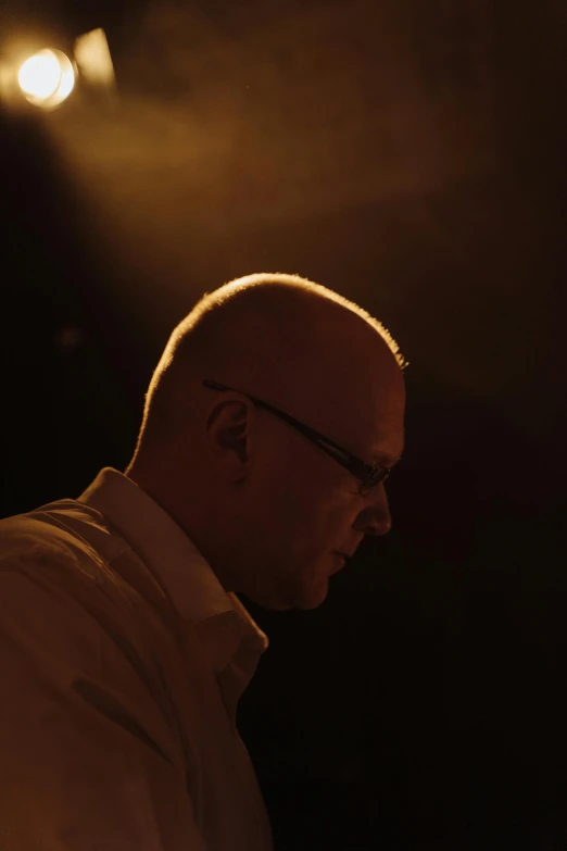 a man playing a keyboard in a dark room, an album cover, by Peter Churcher, portrait of bald, man with glasses, soft light from the side, on stage