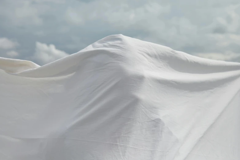 a white sheet sitting on top of a beach, by Christo, unsplash contest winner, conceptual art, snow camouflage, pbr material, zoom shot, made of fabric