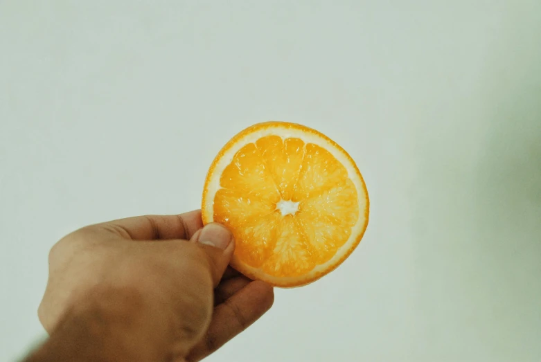 a person holding an orange in their hand, by Gavin Hamilton, trending on pexels, yellow aureole, made of food, detailed acrylic, flat minimalistic