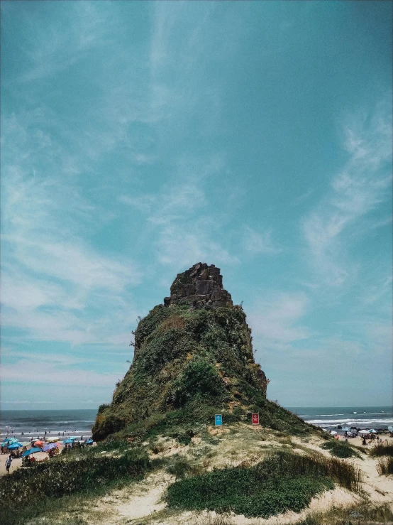 a group of people standing on top of a sandy beach, giant imposing mountain, trending on vsco, bali, ((monolith))