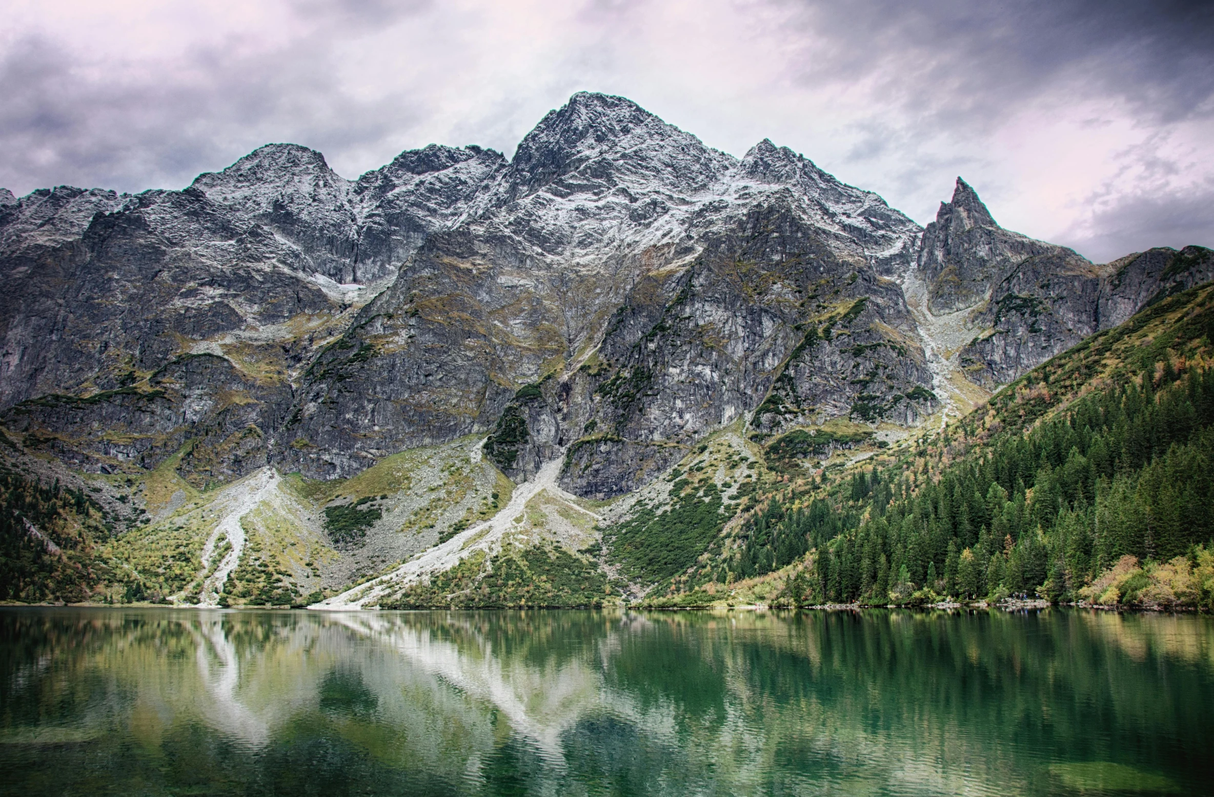 a body of water with a mountain in the background, by Adam Marczyński, pexels contest winner, hurufiyya, poland, brilliant peaks, ornately detailed, grey