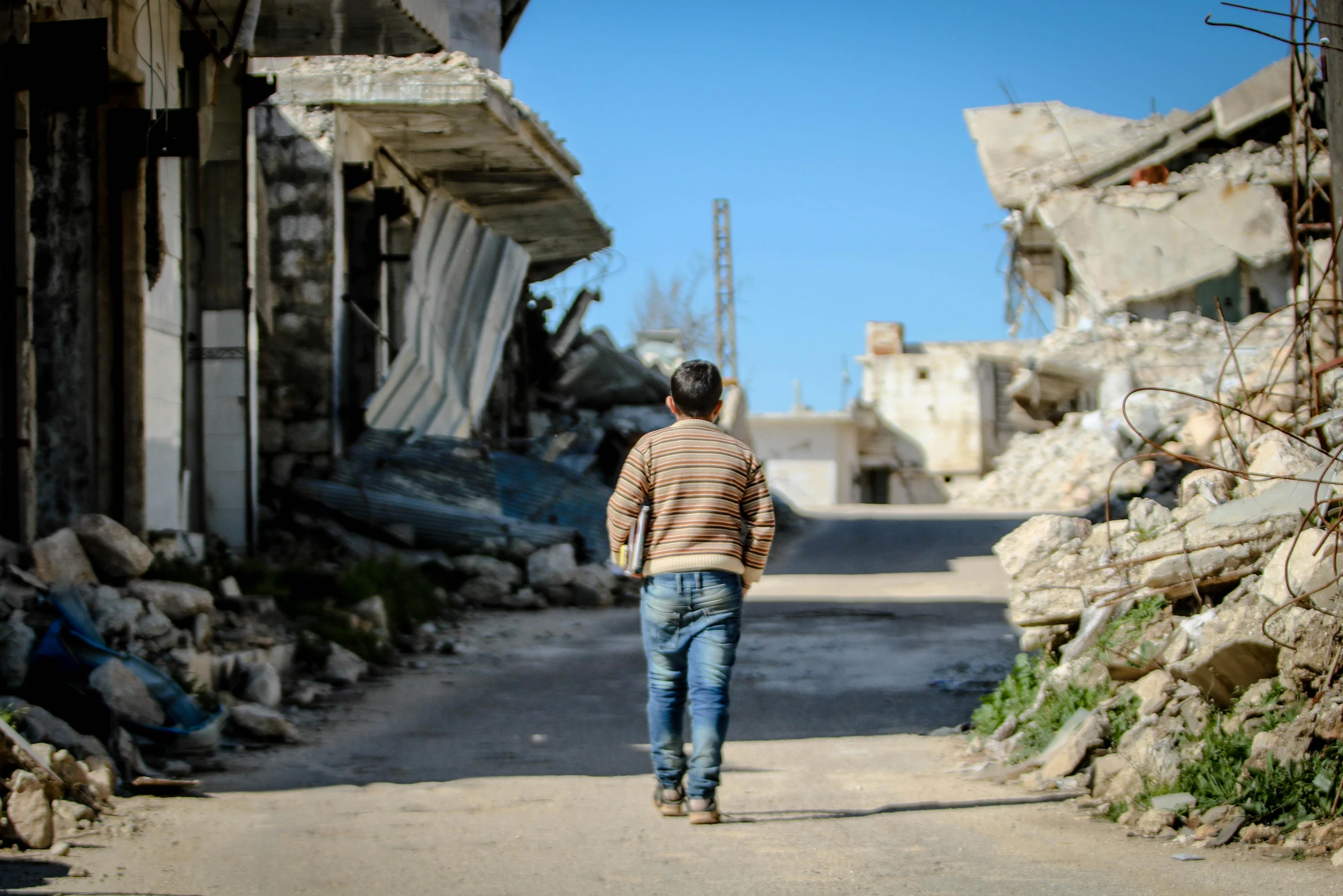 a man walking down the middle of a street, dau-al-set, standing in ruins, promo image, politics, back view. nuri iyem