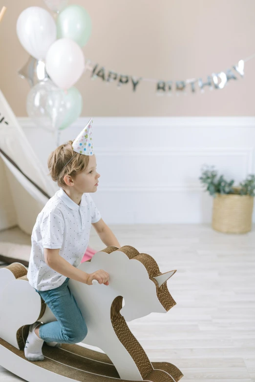 a little boy that is sitting on a rocking horse, trending on unsplash, party balloons, white, cardboard, thumbnail