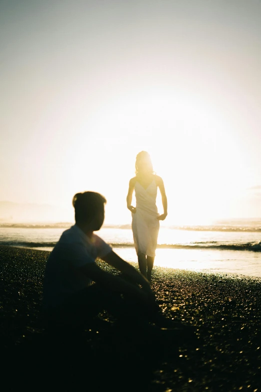 a couple of people sitting on top of a beach, unsplash, romanticism, bathed in light, standing straight, high light on the left, talking