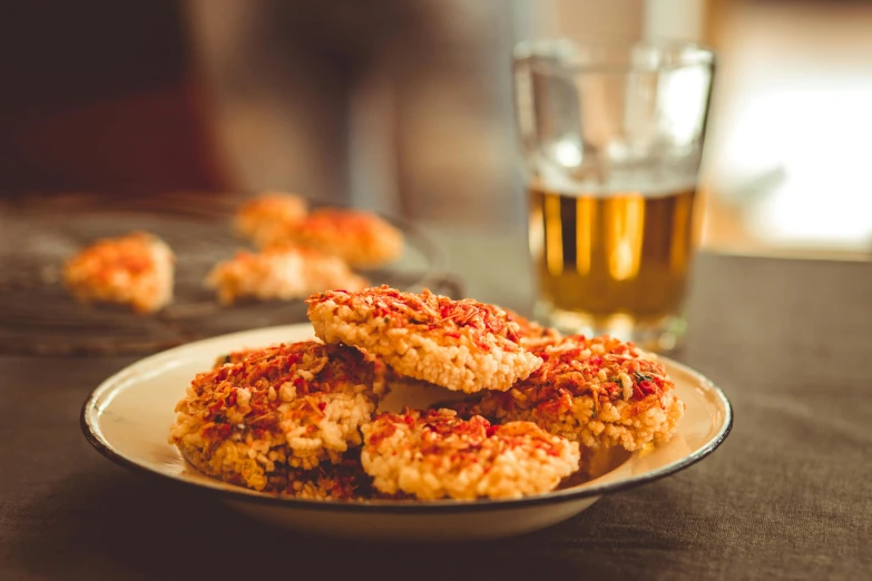 a plate of food sitting on a table next to a glass of beer, pexels, cookies, red and gold, olivia kemp, crispy