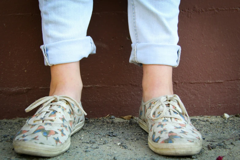 a close up of a person's shoes in front of a brick wall, trending on pexels, wearing pants, delicate patterned, washed out colors, teenager girl