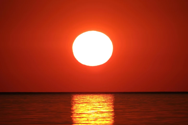 the sun is setting over the water, pexels contest winner, romanticism, big red sun, huge prismatic glowing sun, humid evening, red sea