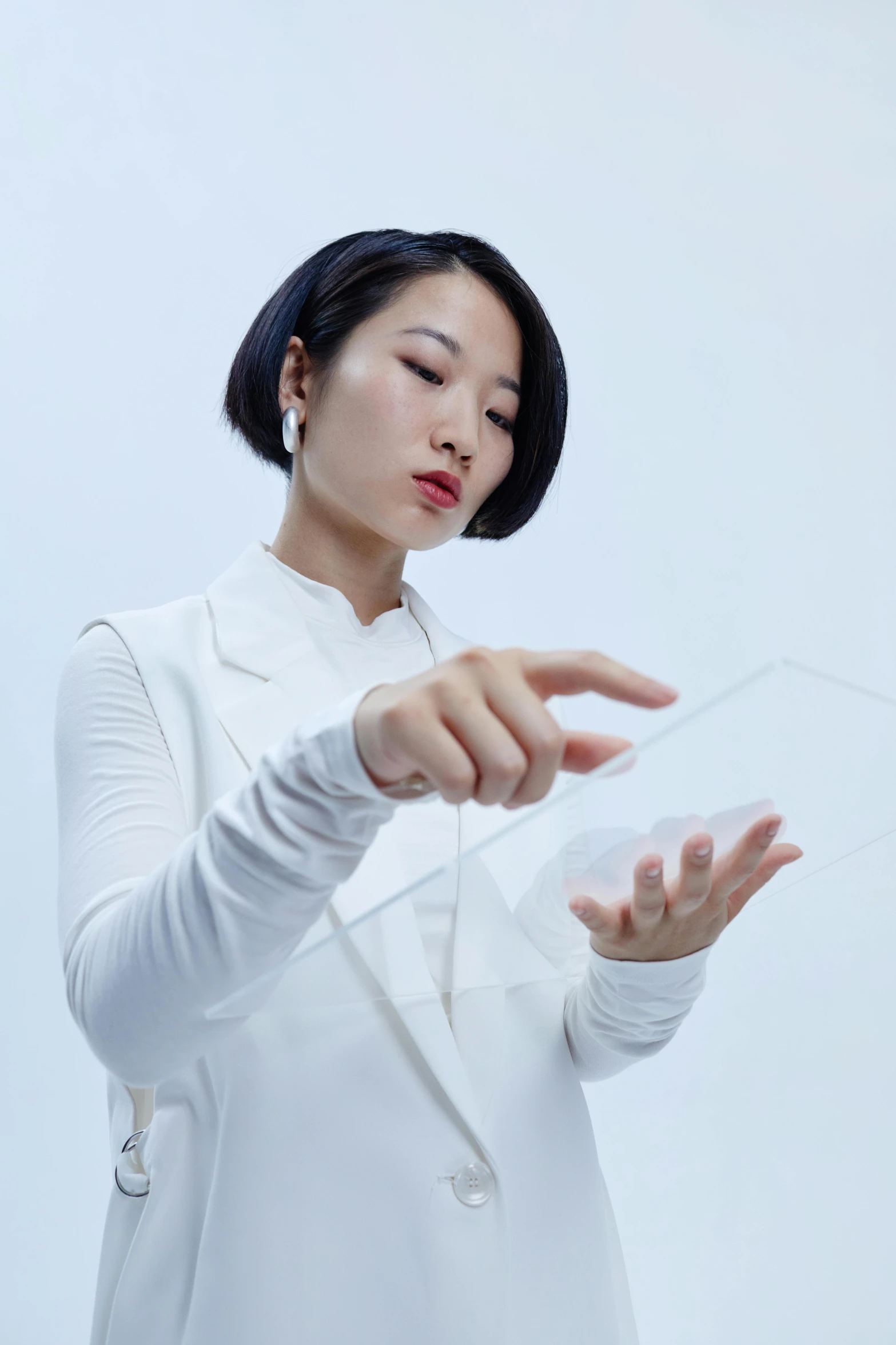 a woman in a white shirt holding a cell phone, an album cover, inspired by Fei Danxu, conceptual art, transparent glass surfaces, modular graphene, partially cupping her hands, looking left