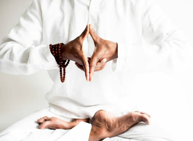 a man in a white shirt is doing yoga, pexels contest winner, hurufiyya, sitting on man's fingertip, wearing brown robes, four hands, smooth intricate