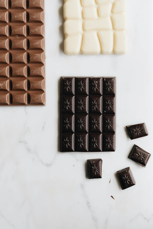 a variety of chocolates laid out on a table, by Jessie Algie, smokey burnt envelopes, milk cubes, embossed, different sizes