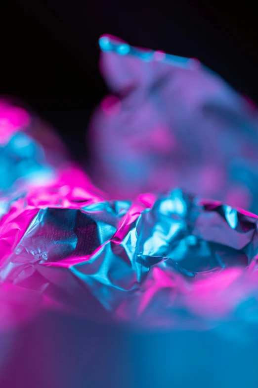 a piece of foil sitting on top of a table, a microscopic photo, inspired by Lynda Benglis, pexels contest winner, holography, pink and blue lighting, made of cotton candy, dramatic lighting; 4k 8k, color ( sony a 7 r iv