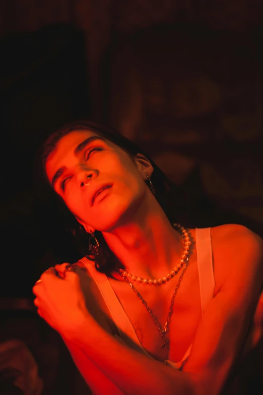 a woman standing in front of a red light, an album cover, inspired by Elsa Bleda, trending on pexels, bauhaus, pearls and chains, androgynous vampire, film still of gal gadot, concert photo