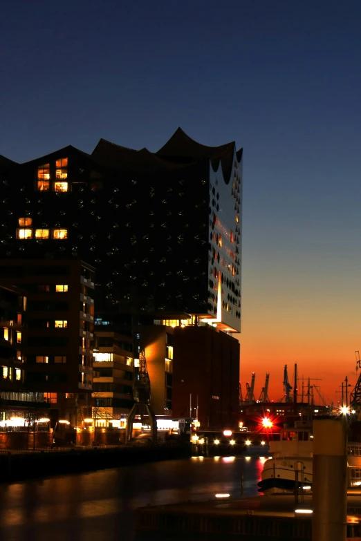 a city street filled with lots of traffic next to tall buildings, by Jakob Emanuel Handmann, flickr, viewed from the harbor, light illumination at sunset, hannover, frank gehry