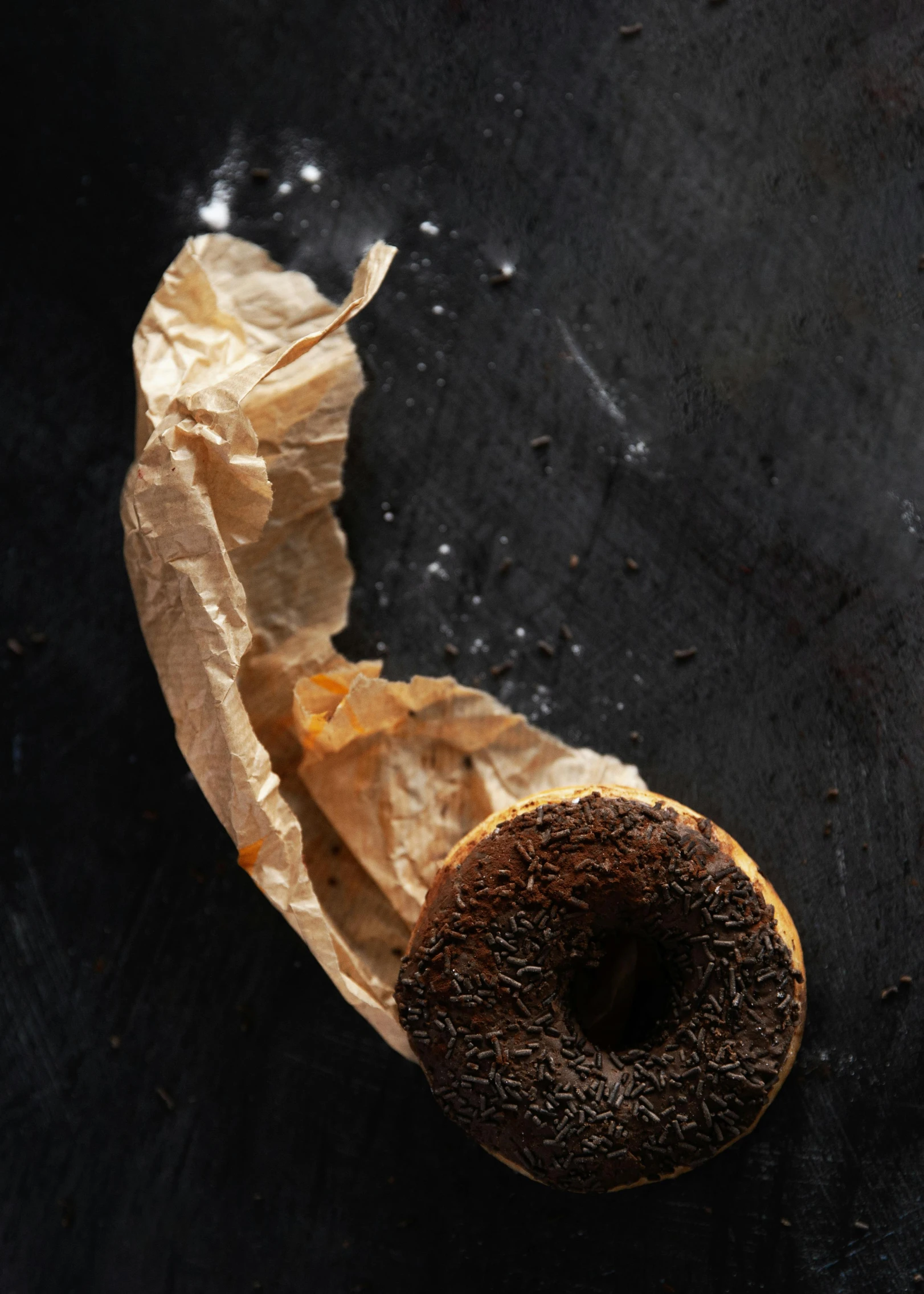 a bagel with a bite taken out of it, a portrait, by Alison Geissler, hurufiyya, matte black paper, photographed for reuters, chocolate, aged and weathered