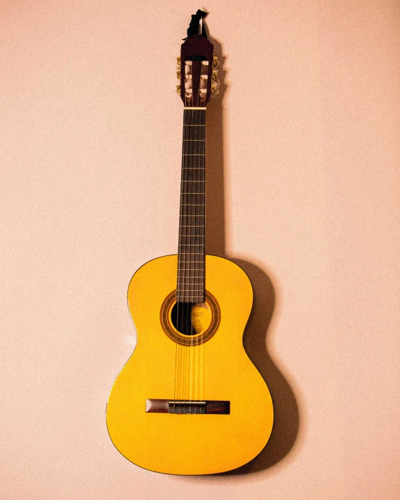 a close up of a guitar on a wall, inspired by Germán Londoño, unsplash, minimalism, yellow backdrop, google arts and cultures, portrait photo, sojourn from overwatch