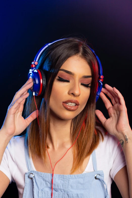 a woman in overalls listening to music with headphones, trending on pexels, blue and red lights, avatar image, middle eastern, close - up studio photo