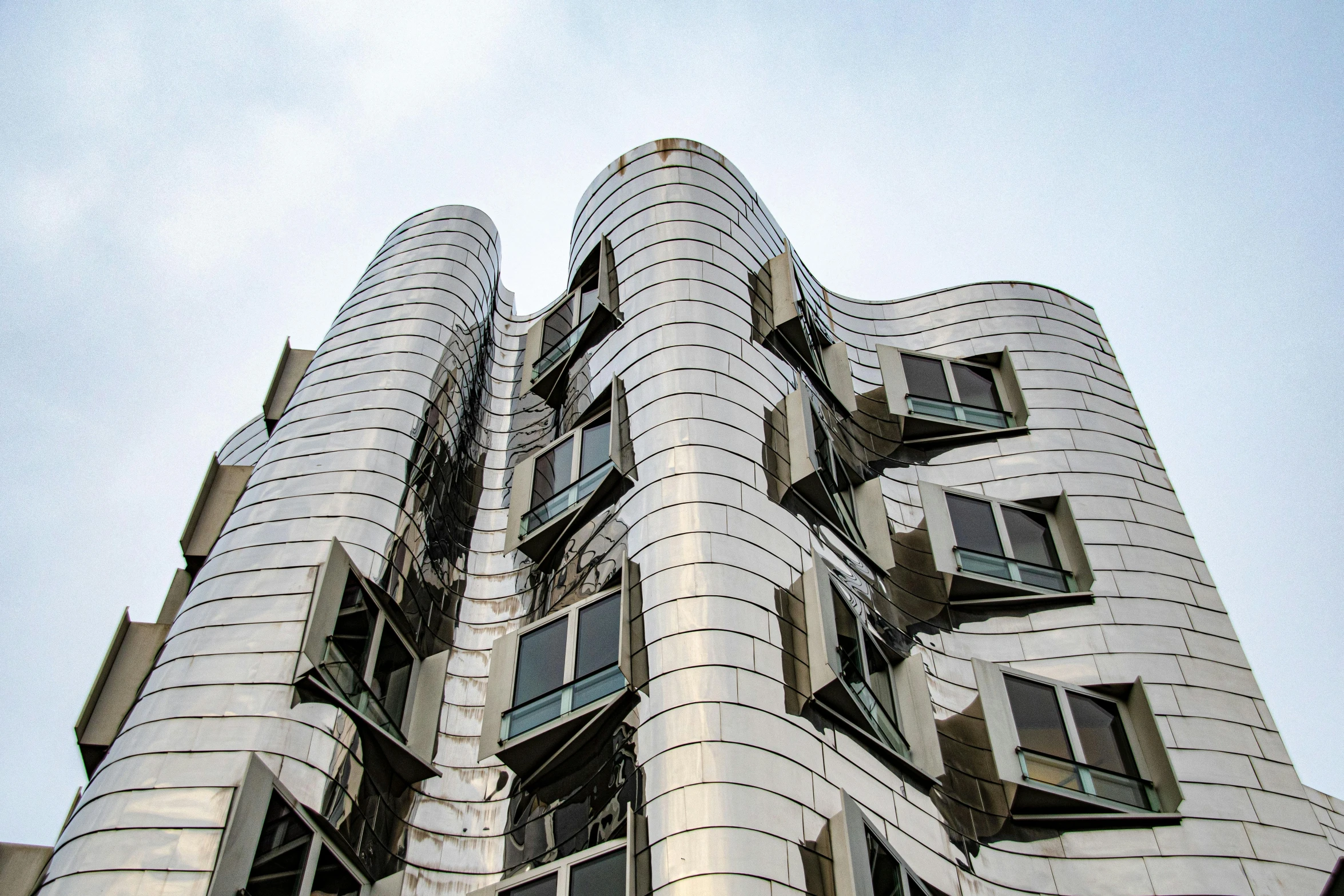 a very tall building with lots of windows, inspired by Zaha Hadid, unsplash contest winner, art nouveau, shiny silver, frank gehry, looking towards camera, waving