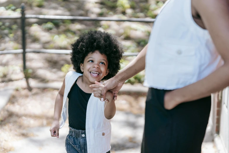 a close up of a person holding a child's hand, a portrait, by Nina Hamnett, pexels contest winner, dark short curly hair smiling, focus on full - body, big afro, sydney park