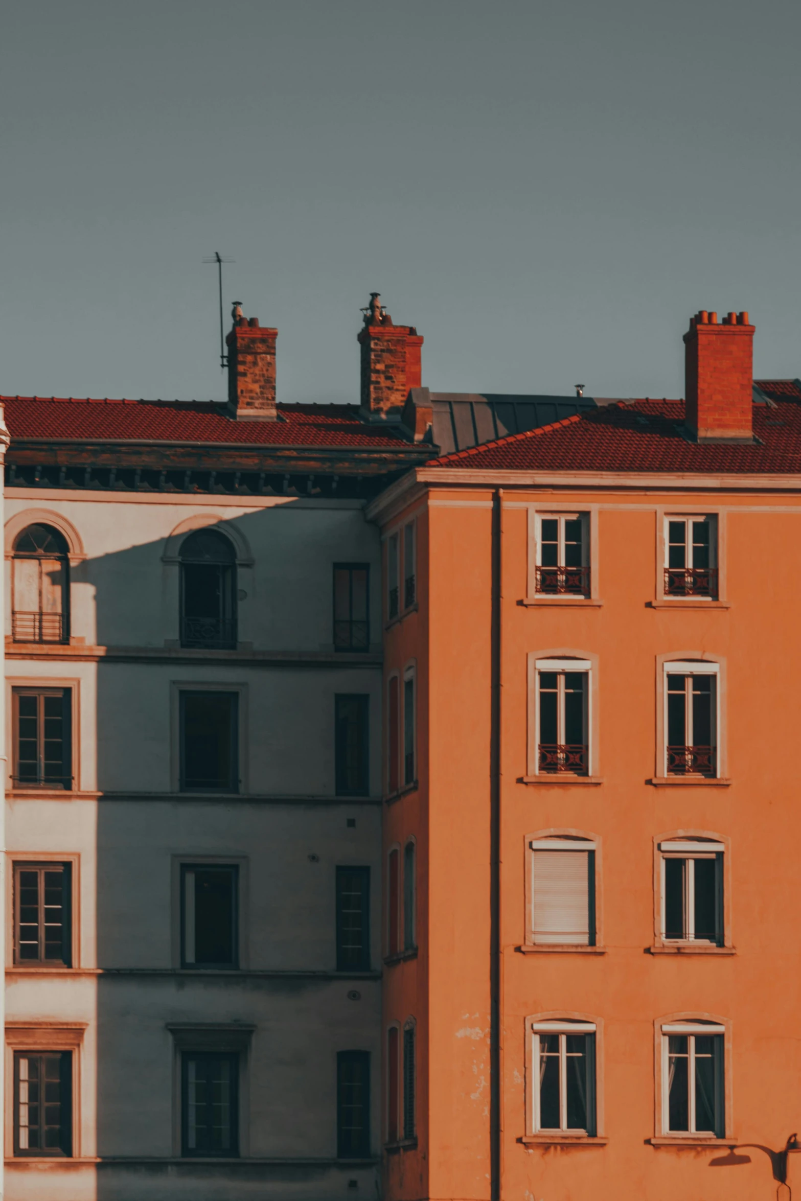 a couple of buildings that are next to each other, by Raphaël Collin, unsplash contest winner, warm colour scheme, afternoon light, single flat colour, late summer evening