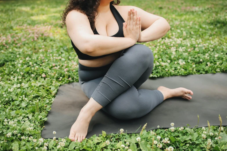 a woman sitting on a yoga mat in the grass, trending on pexels, figuration libre, plus-sized, grey, upper body image, tights