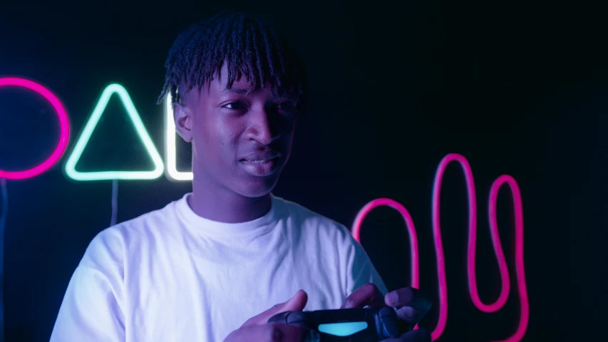 a young man holding a game controller in front of neon signs, pexels contest winner, black teenage boy, bisexual lighting, looking towards camera, low quality photo
