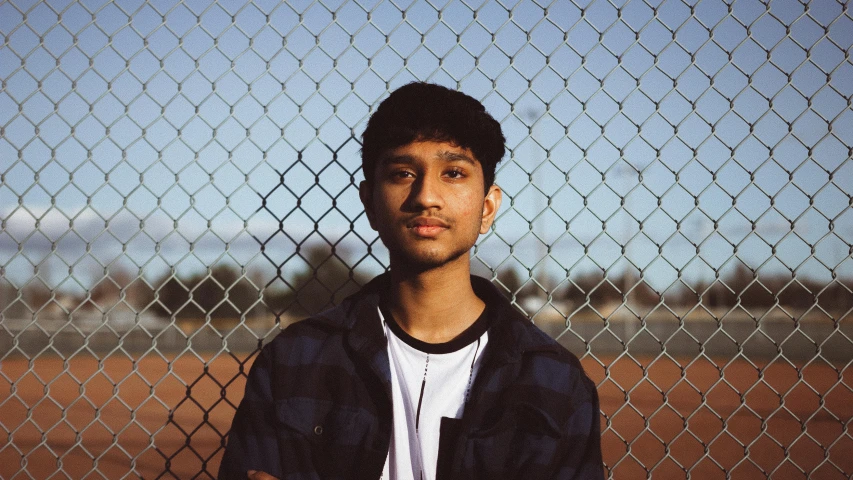 a young man standing in front of a chain link fence, an album cover, by Max Dauthendey, unsplash, hurufiyya, ((portrait)), portrait of gigachad, headshot portrait, jayison devadas