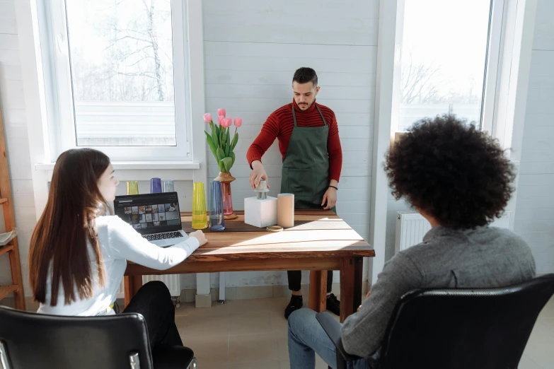 a couple of people sitting at a table with a laptop, some pouring techniques, man sitting facing away, chemical woekshop, profile image