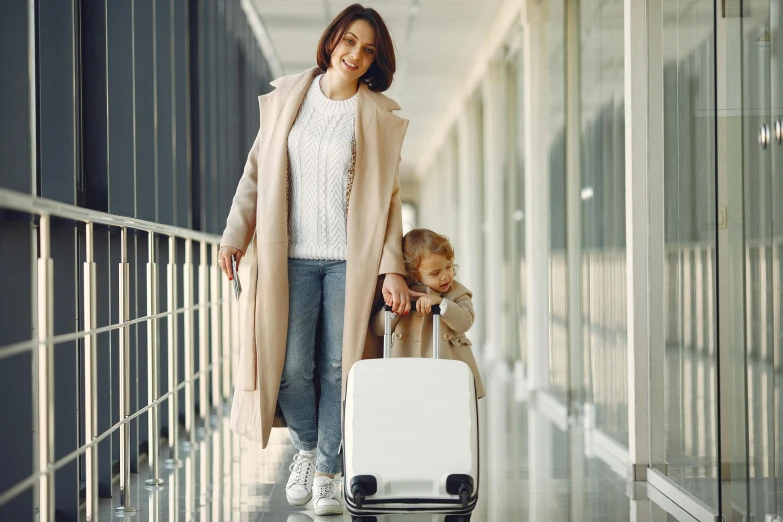 a woman with a child pulling a suitcase, wearing a white winter coat, avatar image, brand, in australia